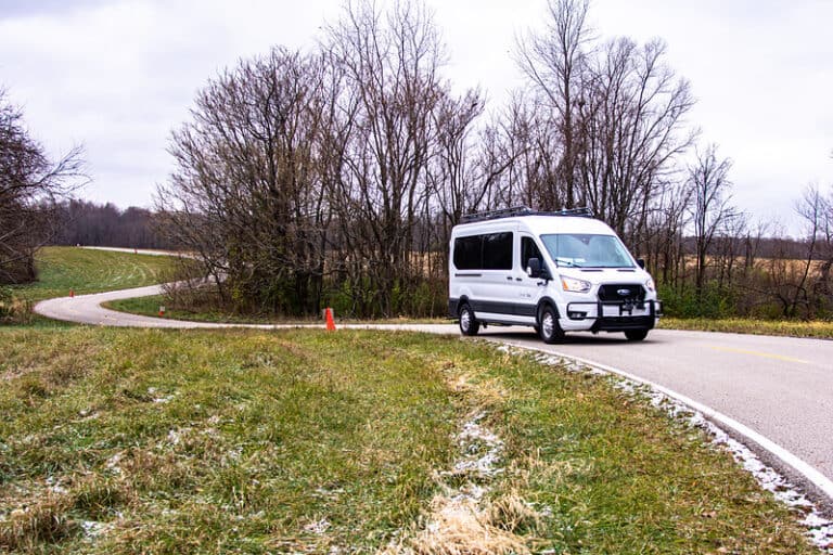 A passenger van travels along a winding rural road.