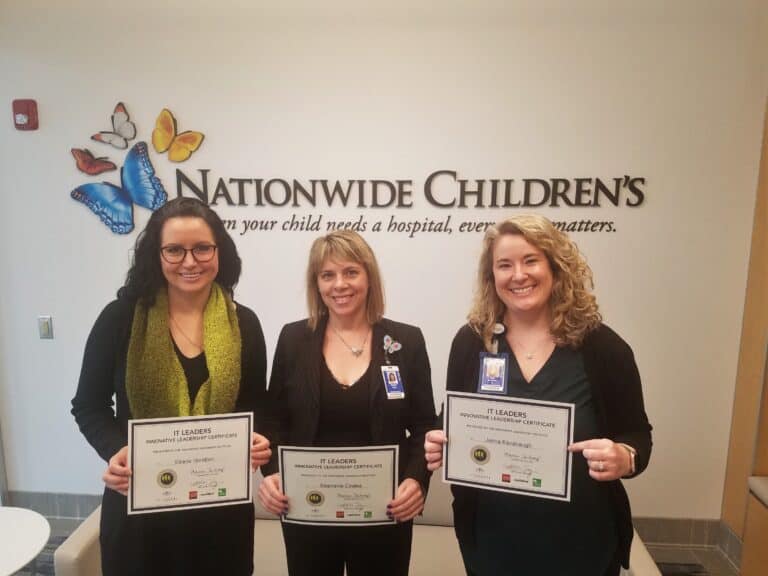 Three people with IT Leader program certificates standing in front of a Nationwide Children's Hospital sign.